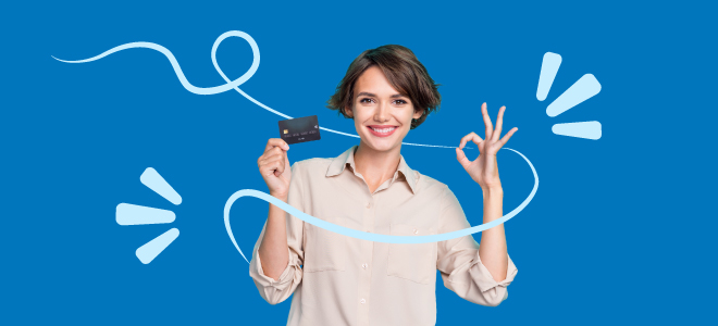 Donna sorridente che tiene una carta di credito in una mano e fa il gesto “ok” con l’altra, in atteggiamento positivo.