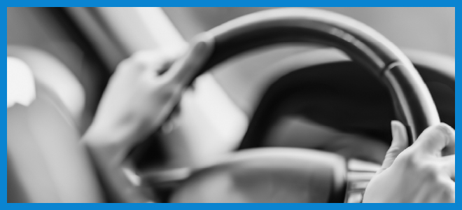 volante di un'automobile su cui sono poggiate delle mani